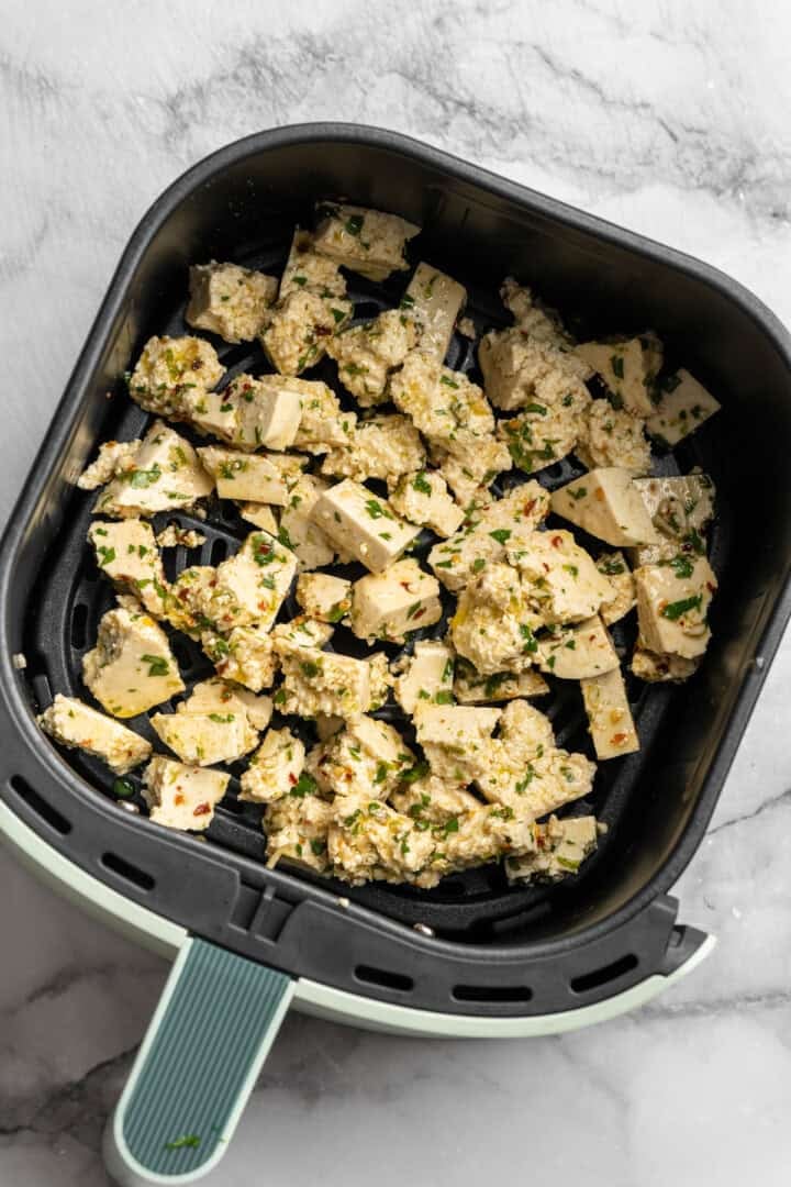 Bursting with zippy lime, sweet, citrusy cilantro, and a hit of garlic, this golden-brown cilantro lime marinated tofu is perfect for tacos. Cilantro lime marinaded tofu spread into the basket of an air fryer.
