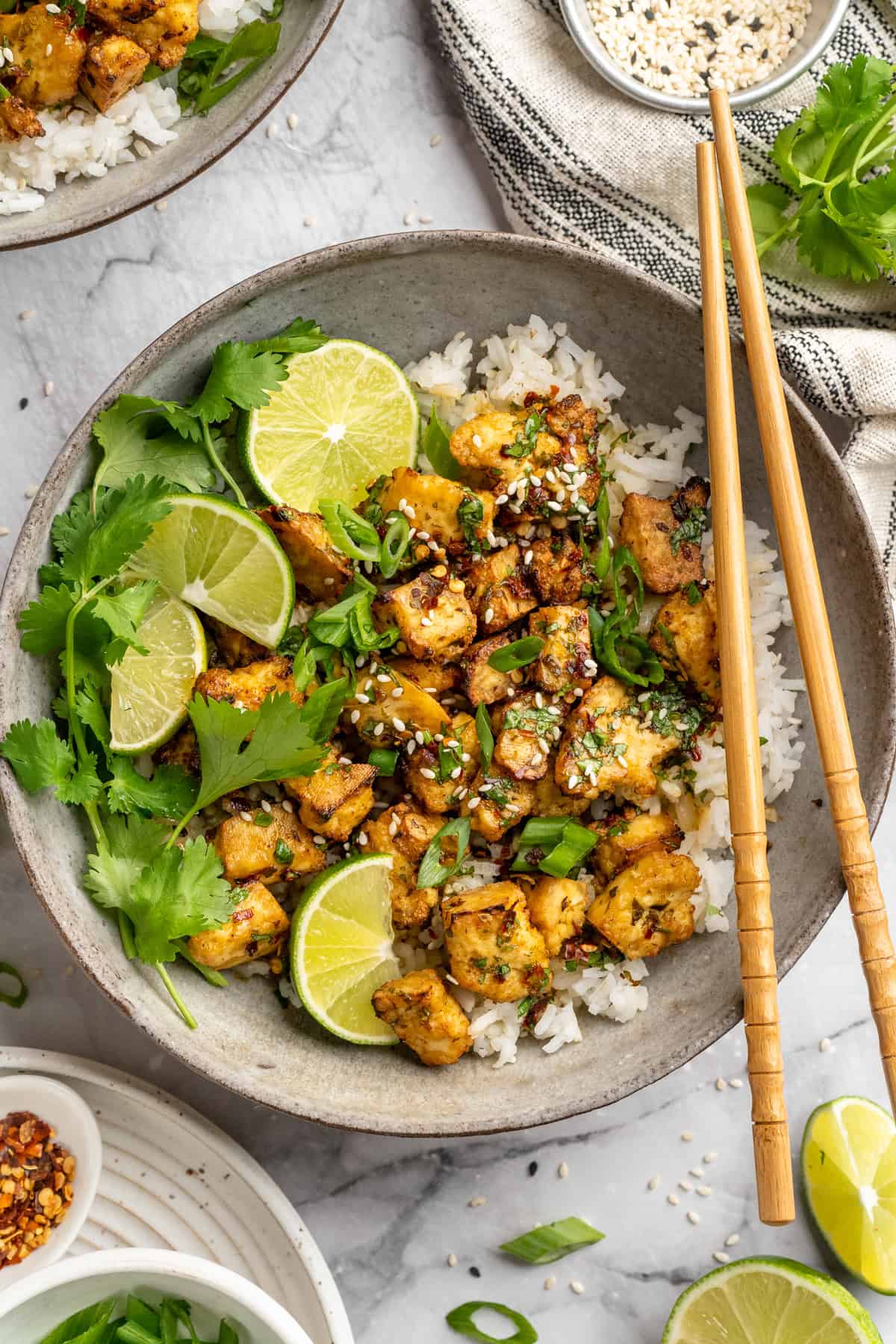 Bursting with zippy lime, sweet, citrusy cilantro, and a hit of garlic, this golden-brown cilantro lime marinated tofu is perfect for tacos. Overhead image of a bowl of cilantro lime marinated tofu over rice.