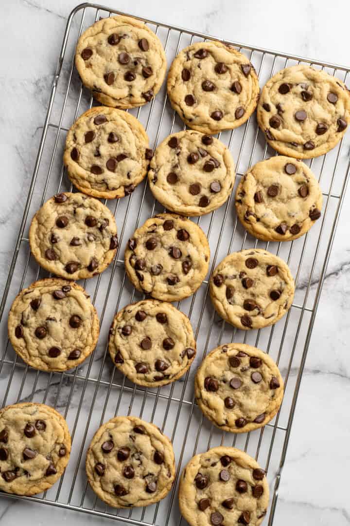 These vegan sourdough chocolate chip cookies are about to up your cookie standards. They're tender and chewy with a subtle sourdough tang. Sourdough discard chocolate chip cookies cooling on a wire wrack.