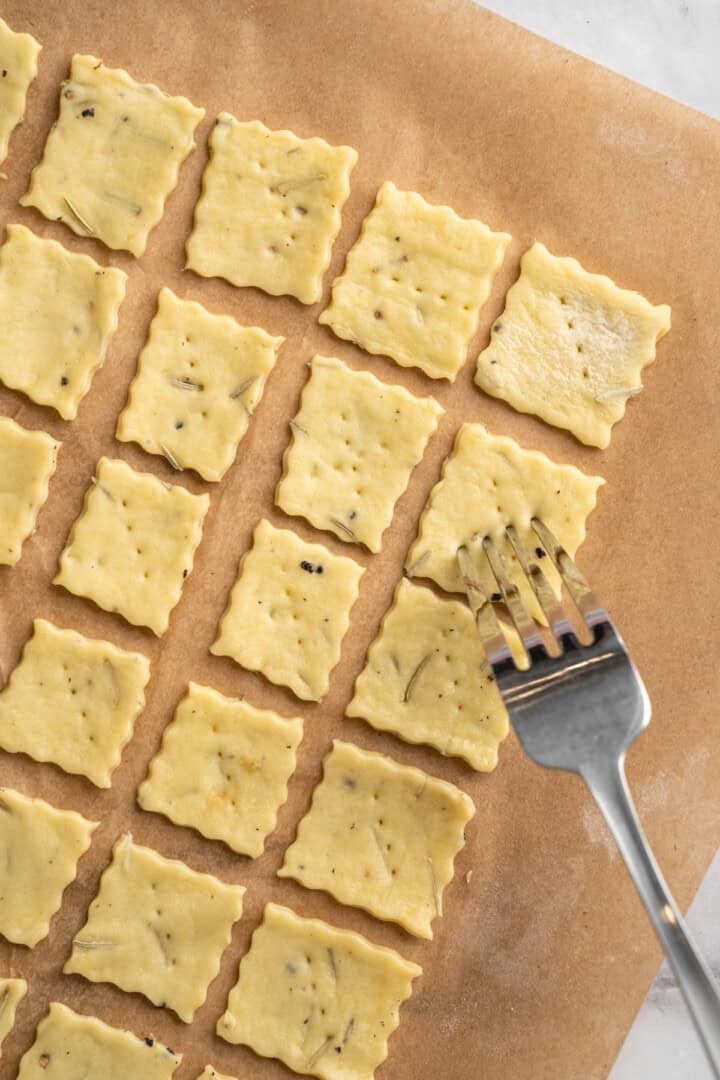 What to do with that sourdough discard? These easy sourdough discard crackers are crunchy, crispy, and flaky, with that best sourdough tang. Poking squares of unbaked sourdough discard crackers with a fork.
