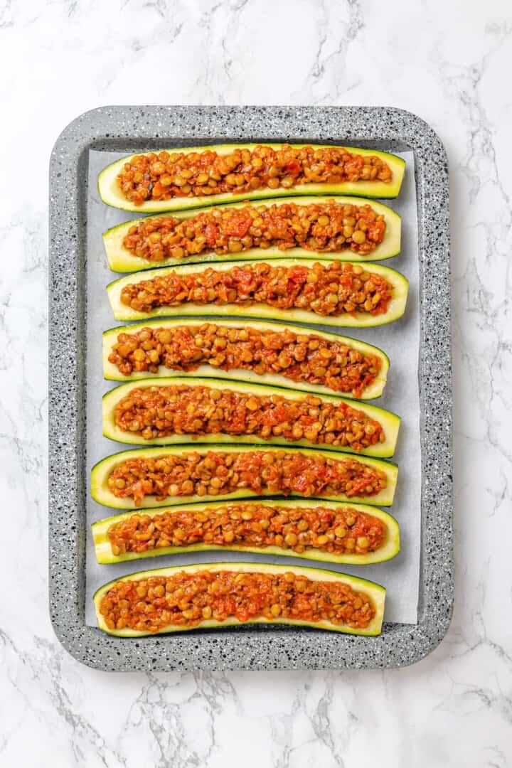 These stuffed zucchini boats are loaded with rich marinara sauce, melty vegan mozzarella, and protein-packed lentils. The perfect summer side. Zucchini boats stuffed with a lentil filling.