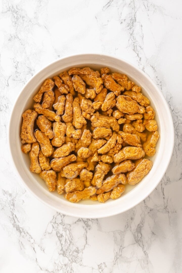 Vegan popcorn chicken features tender soy curls in a crunchy KFC-style breading served with a maple Dijon sauce. It beats takeout any day! Soaking soy curls in veggie broth.