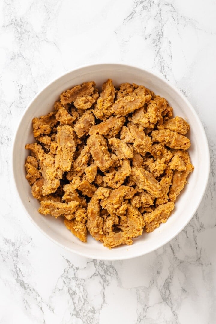 Vegan popcorn chicken features tender soy curls in a crunchy KFC-style breading served with a maple Dijon sauce. It beats takeout any day! Hydrated, drained soy curls in a bowl.