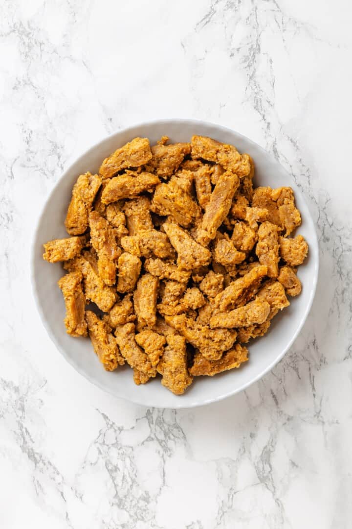 Vegan popcorn chicken features tender soy curls in a crunchy KFC-style breading served with a maple Dijon sauce. It beats takeout any day! Hydrated, drained, and squeezed soy curls in a bowl.