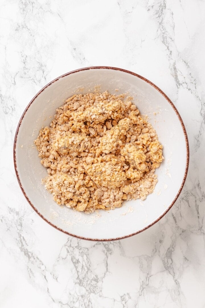 Vegan popcorn chicken features tender soy curls in a crunchy KFC-style breading served with a maple Dijon sauce. It beats takeout any day! Tossing soy curls dipped in vegan buttermilk in KFC-style breading.