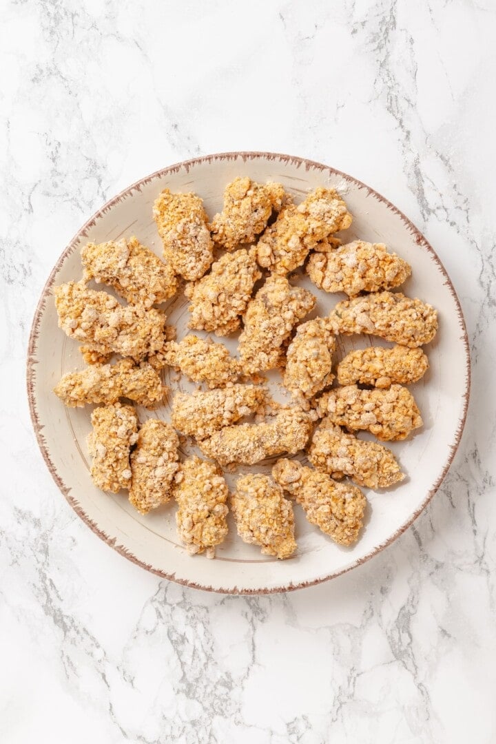 Vegan popcorn chicken features tender soy curls in a crunchy KFC-style breading served with a maple Dijon sauce. It beats takeout any day! Breaded soy curls ready to be fried.