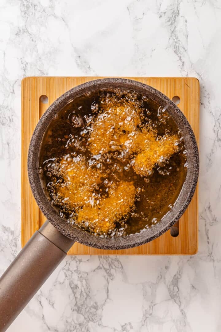 Vegan popcorn chicken features tender soy curls in a crunchy KFC-style breading served with a maple Dijon sauce. It beats takeout any day! Frying vegan popcorn chicken in hot oil.