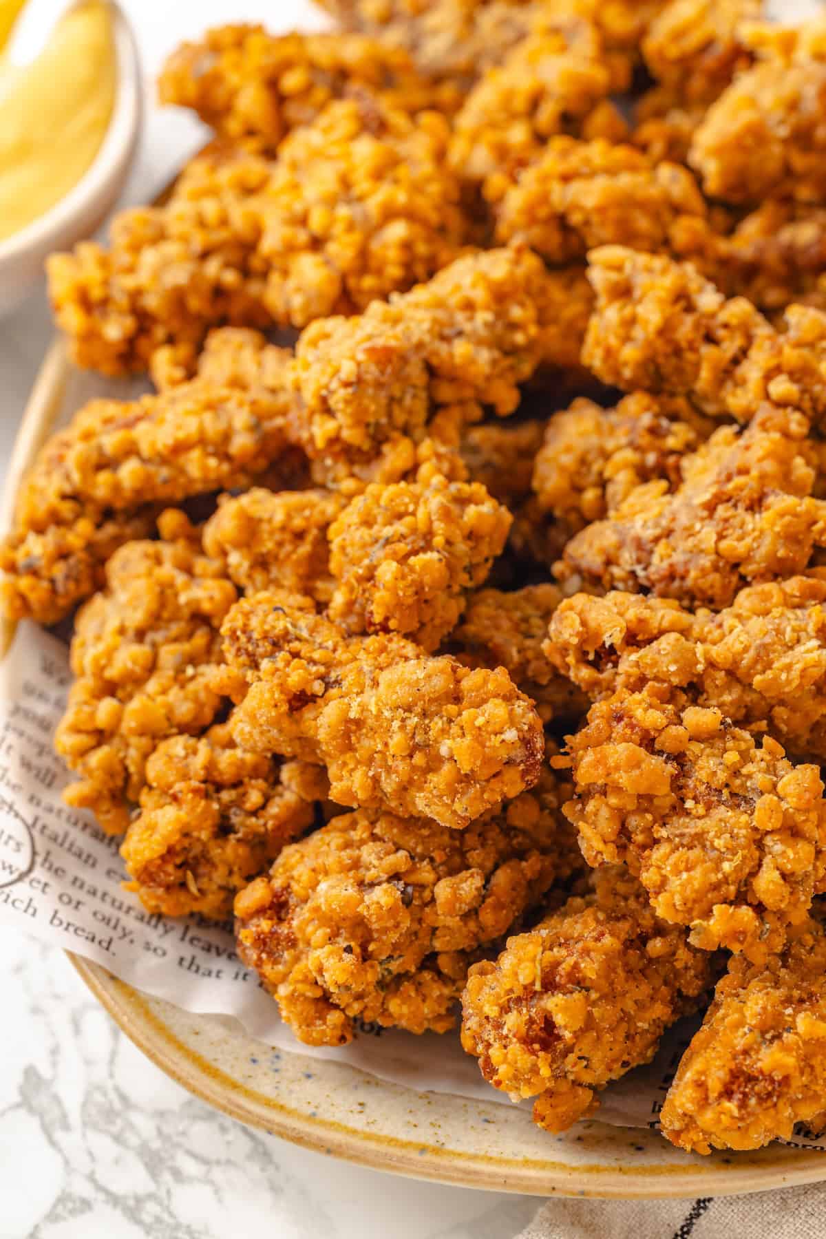 Vegan popcorn chicken features tender soy curls in a crunchy KFC-style breading served with a maple Dijon sauce. It beats takeout any day! A platter loaded with vegan popcorn chicken.