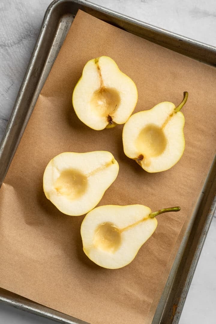 These easy, tender cinnamon baked pears are perfectly caramelized in a glossy sauce of maple syrup, cinnamon, and their own sweet juices. 4 pear halves arranged, cut-side-up, on a baking sheet.