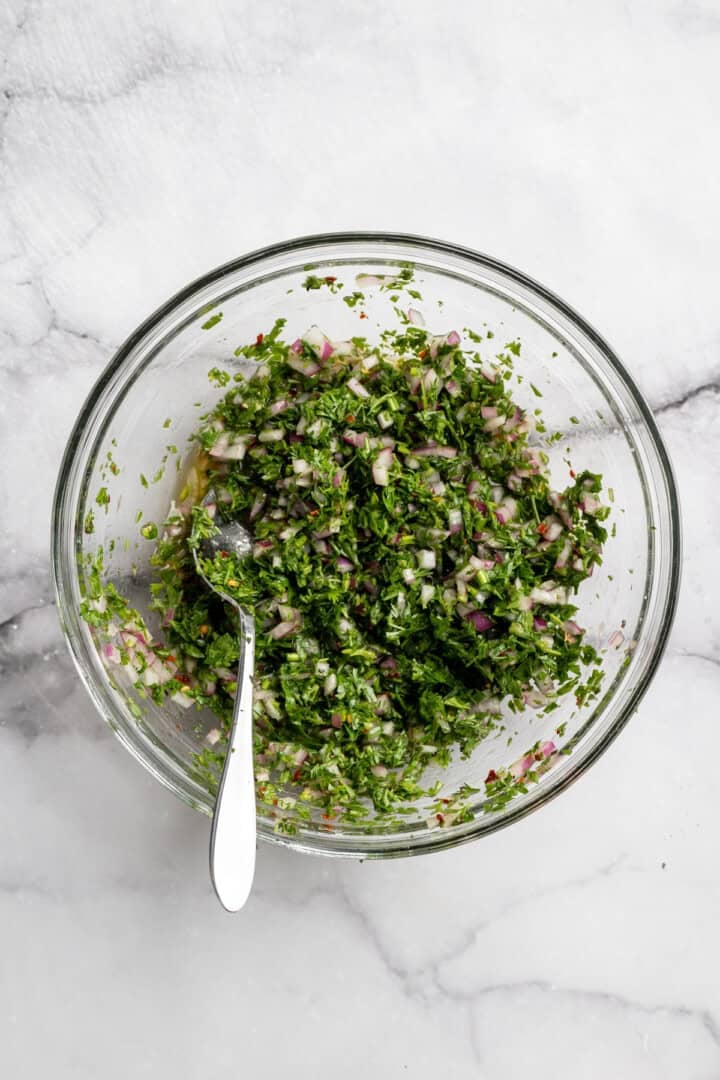 These perfectly caramelized maple roasted carrots are served with a vibrant chimichurri made from the carrot greens themselves. Carrot top chimichurri in a bowl.