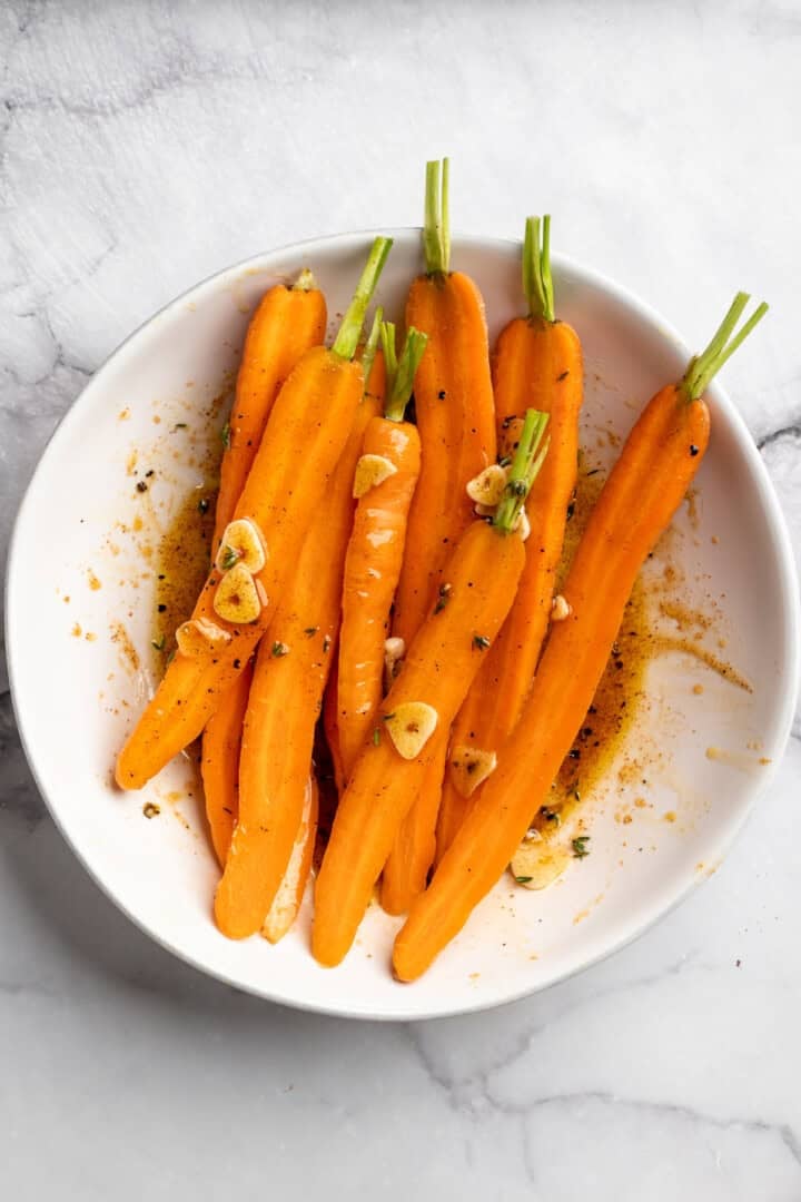 These perfectly caramelized maple roasted carrots are served with a vibrant chimichurri made from the carrot greens themselves. Tossing carrots in a mixture of garlic, coconut oil, maple syrup, thyme, and seasonings.