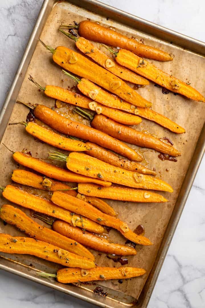 These perfectly caramelized maple roasted carrots are served with a vibrant chimichurri made from the carrot greens themselves. Maple roasted carrots cooling on a sheet pan.