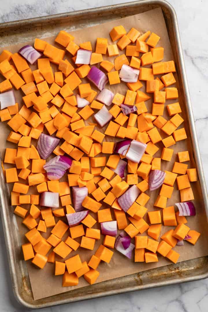 Cubed sweet potatoes and red onion on a sheet pan.