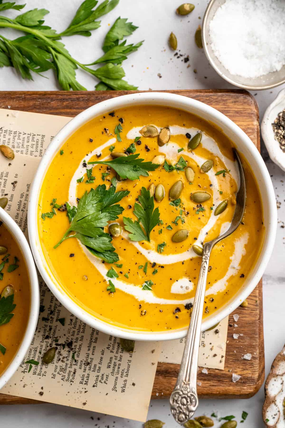 Overhead image of a bowl of sweet potato soup garnished with coconut milk, pumpkin seeds, and parsley.