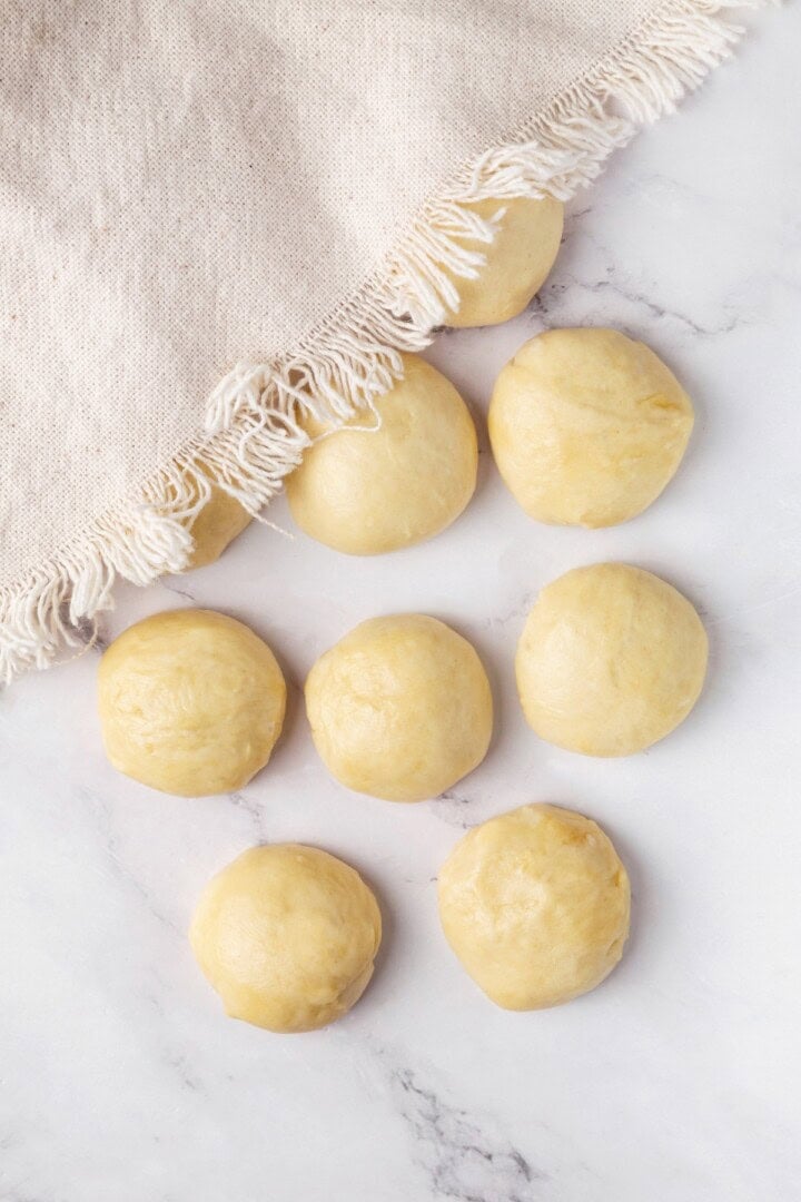 Perfectly soft and chewy, these homemade vegan flour tortillas puff up beautifully in the pan and are ideal for your next burrito. Covering ten balls of vegan tortilla dough with a cloth.