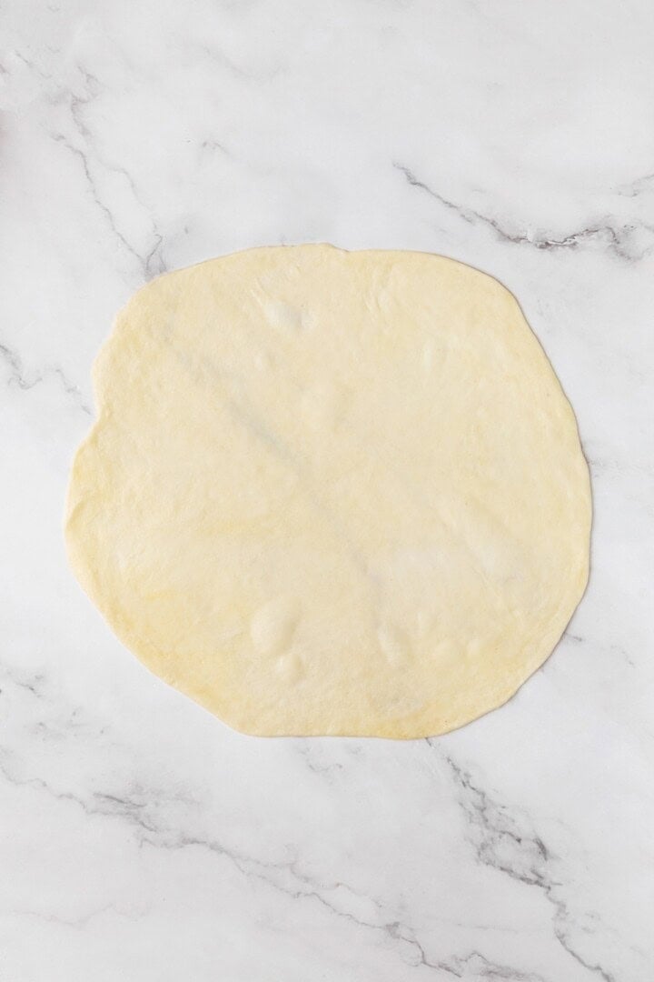 Perfectly soft and chewy, these homemade vegan flour tortillas puff up beautifully in the pan and are ideal for your next burrito. A ball of vegan tortilla dough rolled into a thin circle.