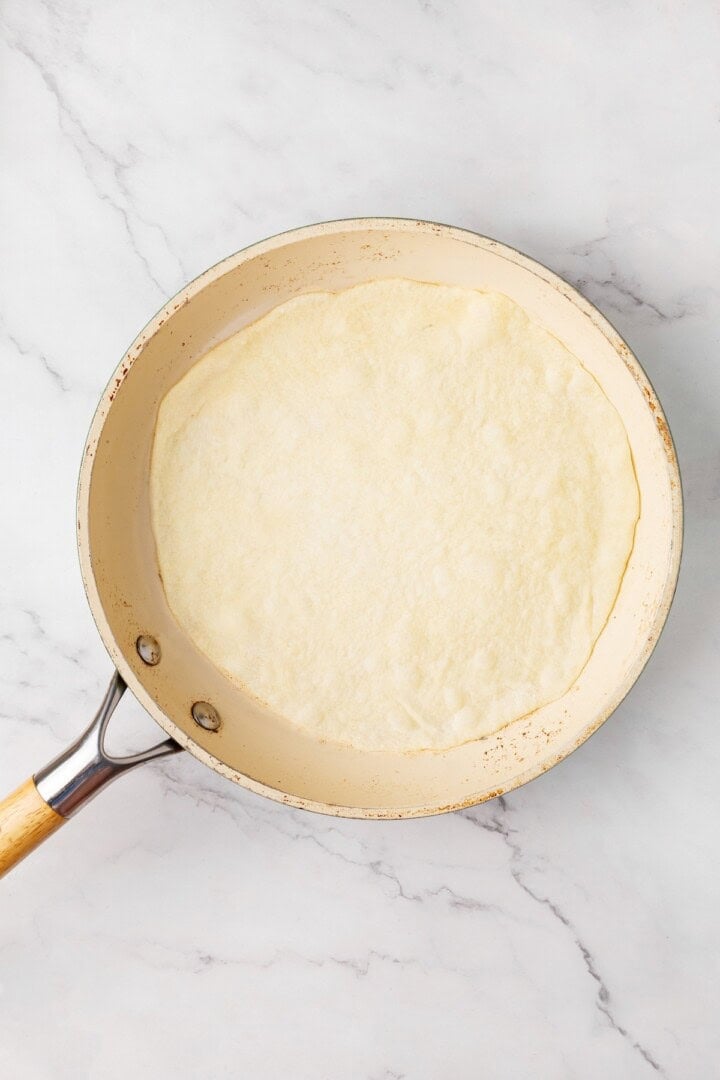 Perfectly soft and chewy, these homemade vegan flour tortillas puff up beautifully in the pan and are ideal for your next burrito. Cooking a vegan tortilla in a dry skillet (side 1).