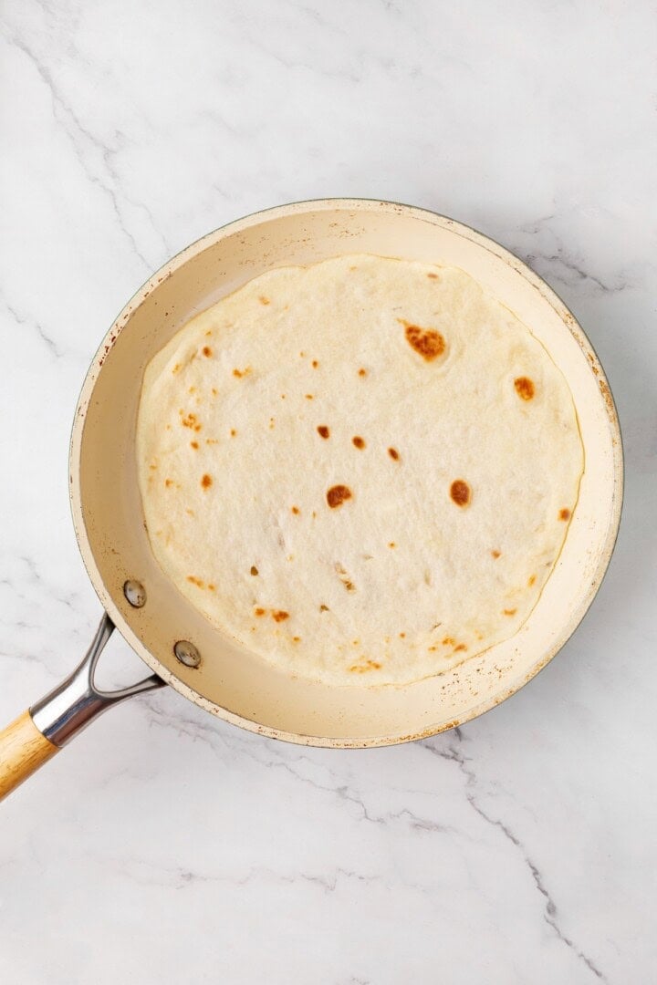 Perfectly soft and chewy, these homemade vegan flour tortillas puff up beautifully in the pan and are ideal for your next burrito. Cooking a vegan tortilla in a dry skillet (side 2).