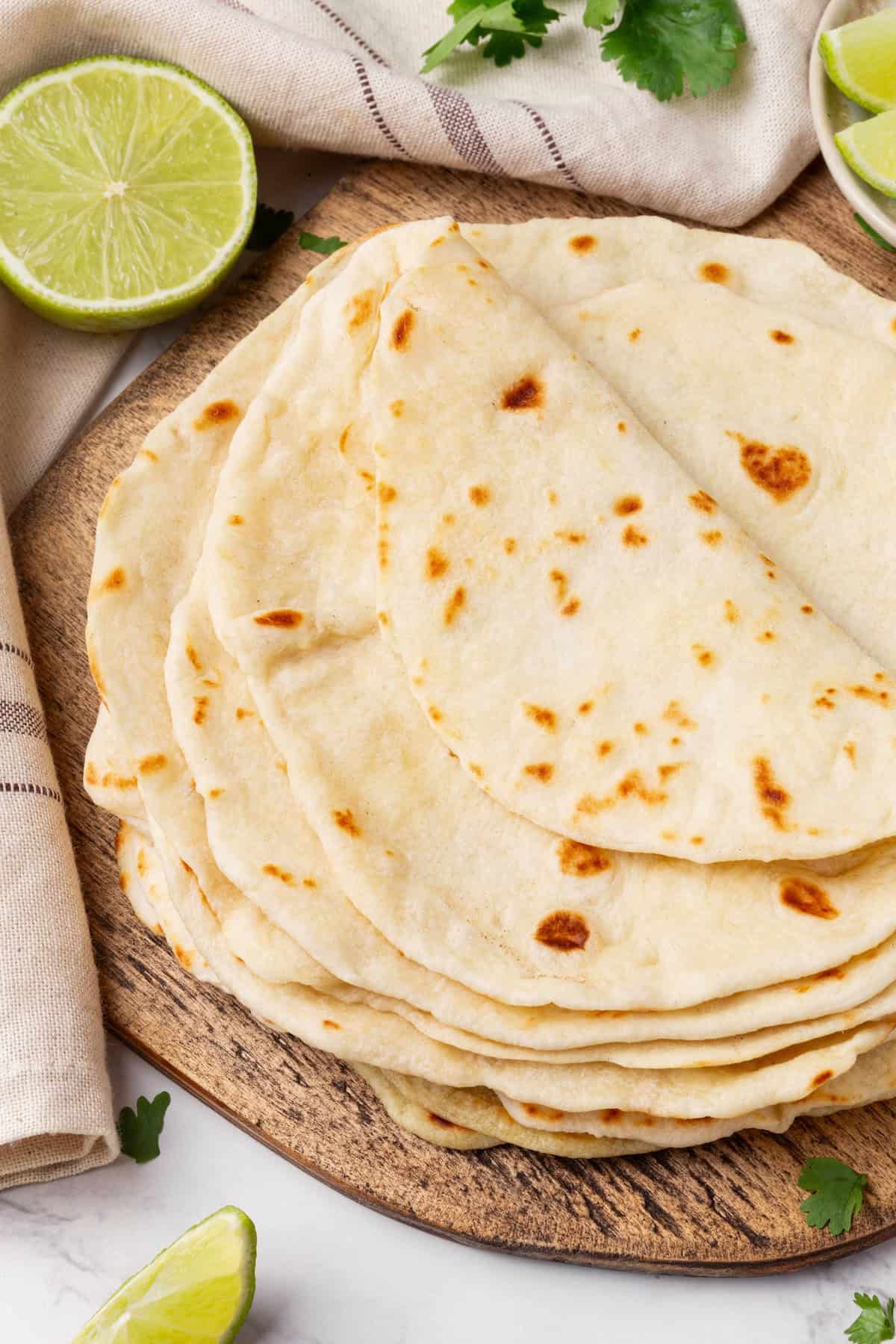 Perfectly soft and chewy, these homemade vegan flour tortillas puff up beautifully in the pan and are ideal for your next burrito. Overhead image of a stack of homemade vegan flour tortillas.