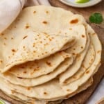 A stack of vegan flour tortillas with several folded on top.