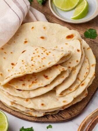 A stack of vegan flour tortillas with several folded on top.