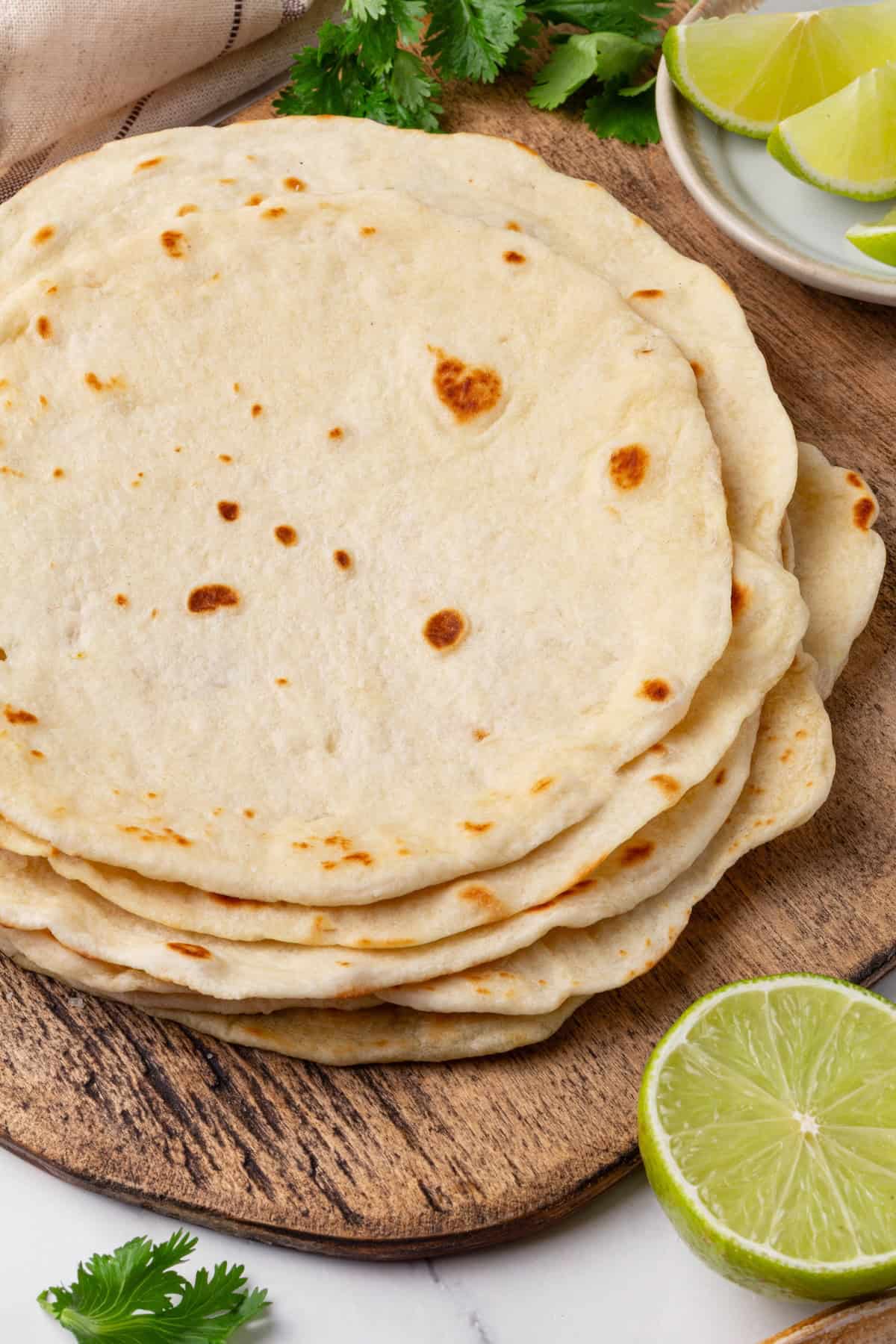 Perfectly soft and chewy, these homemade vegan flour tortillas puff up beautifully in the pan and are ideal for your next burrito. A stack of homemade vegan flour tortillas.