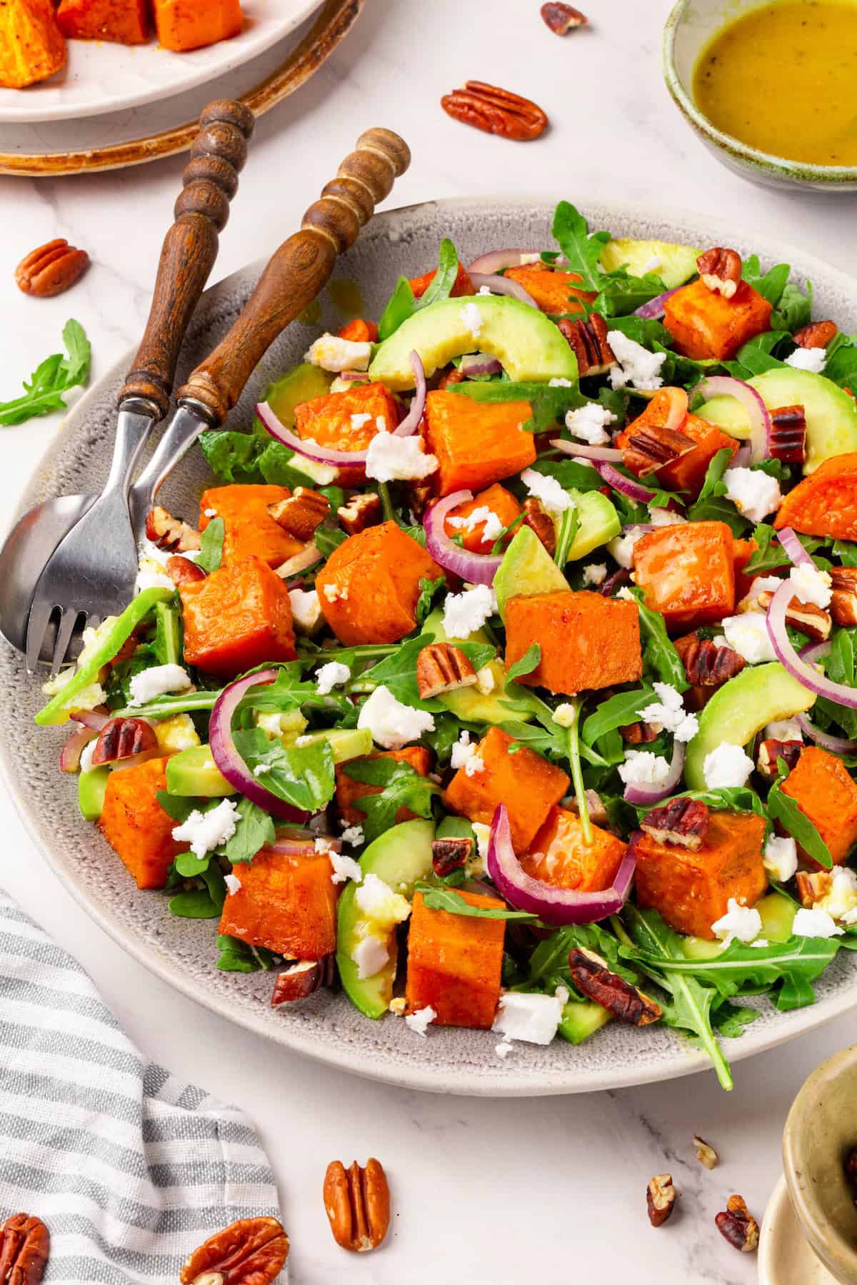This sweet 'n savoury sweet potato salad is full of warm, tender sweet potatoes, crisp, peppery arugula, toasted pecans, and tangy vegan feta. A plate full of roasted sweet potato arugula salad.