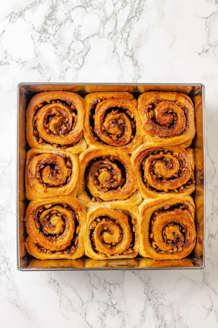 Fabulously fluffy, filled with soft, cinnamony apples, and topped with cream cheese frosting, you need these apple cinnamon rolls now. Baked apple cinnamon rolls cooling in the pan.