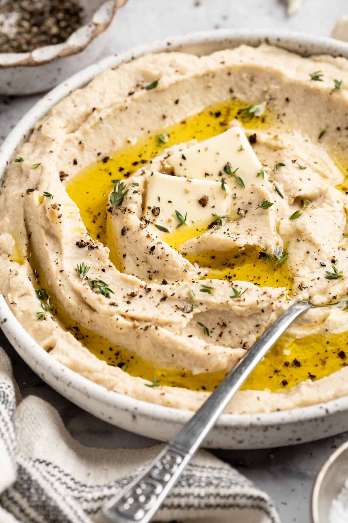 This cauliflower mash is made with roasted cauliflower and garlic for the ultimate sauvoury flavour, and coconut milk for a silky finish. A bowl of vegan mashed cauliflower topped with olive oil.