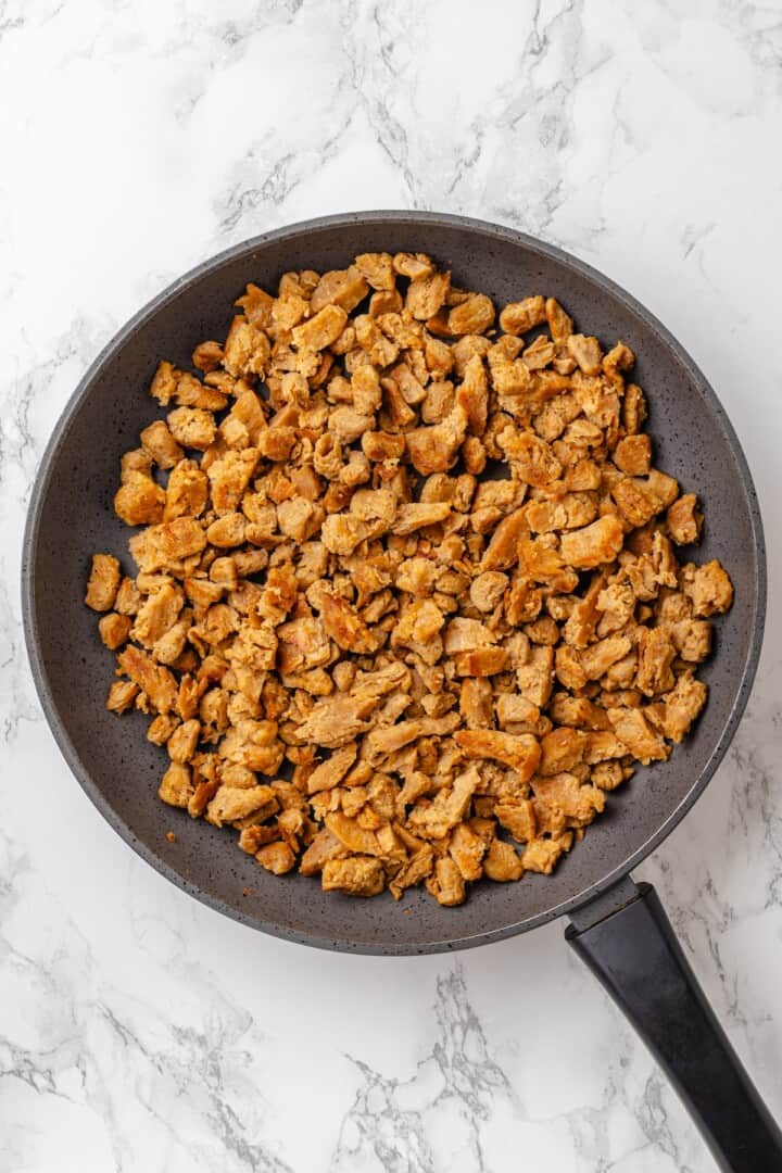 This vegan Philly cheesesteak is piled high with golden-brown, savoury soy curl "steak", tender sautéed veggies, and melted vegan provolone. Drained and squeezed soy curls torn into bite-seized pieces in a pan.