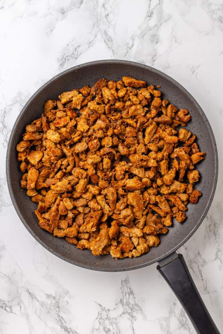 This vegan Philly cheesesteak is piled high with golden-brown, savoury soy curl "steak", tender sautéed veggies, and melted vegan provolone. Golden brown soy curl "steak" in a skillet.