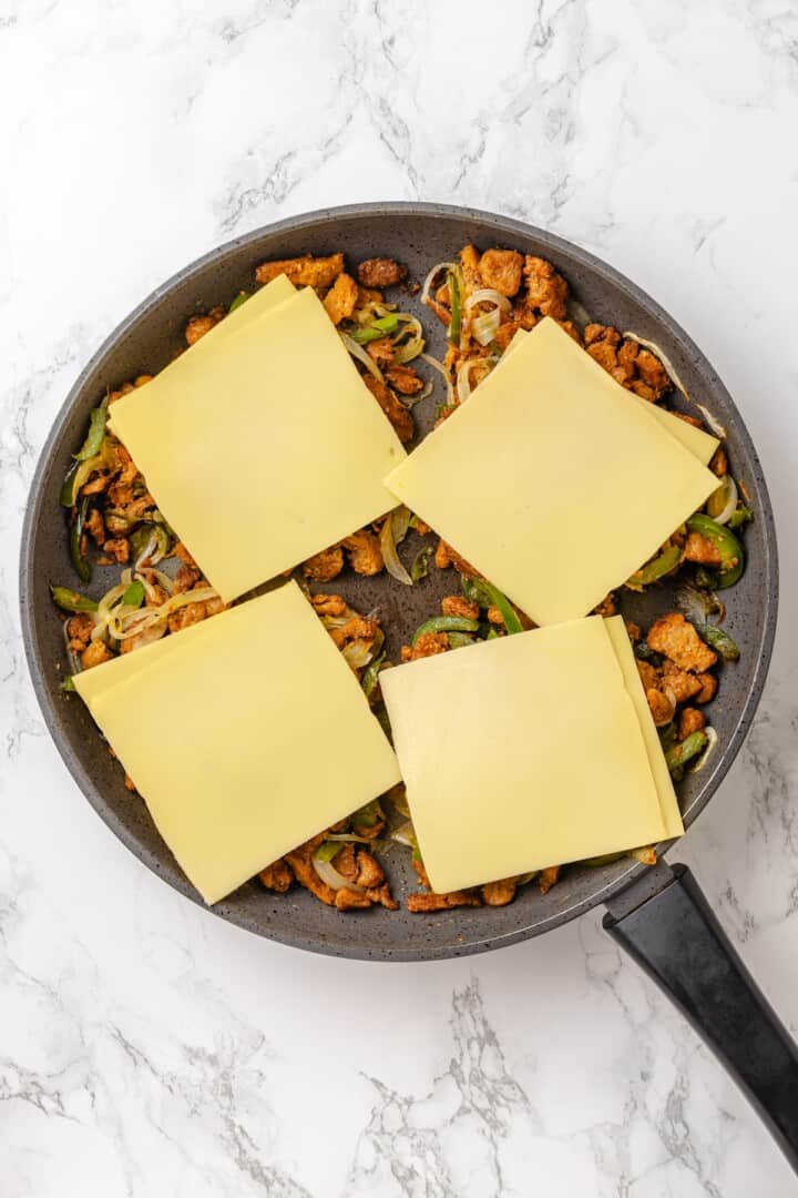 This vegan Philly cheesesteak is piled high with golden-brown, savoury soy curl "steak", tender sautéed veggies, and melted vegan provolone. Topping four portions of Vegan Philly cheesesteak filling with vegan provolone cheese.