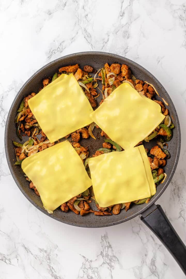 This vegan Philly cheesesteak is piled high with golden-brown, savoury soy curl "steak", tender sautéed veggies, and melted vegan provolone. Four portions of Vegan Philly cheesesteak filling topped with melted vegan provolone cheese.