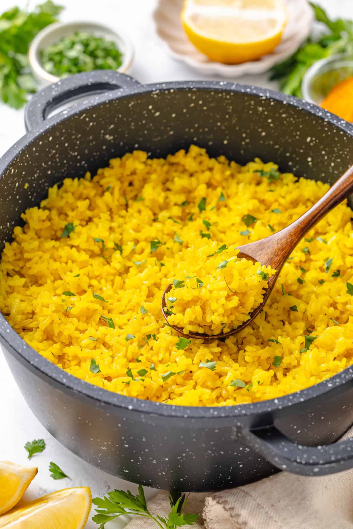 This easy yellow rice is toasted with peppery turmeric and warming cumin and simmered to fluffy perfection in veggie broth. A spoon dipping into a saucepan of fluffy yellow rice.