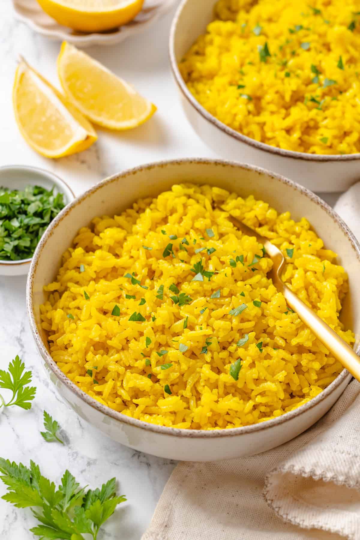 This easy yellow rice is toasted with peppery turmeric and warming cumin and simmered to fluffy perfection in veggie broth. A bowl of fluffy vegan yellow rice garnished with fresh parsley.